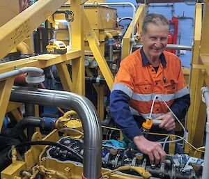 A man in hi viz works on a yellow generator