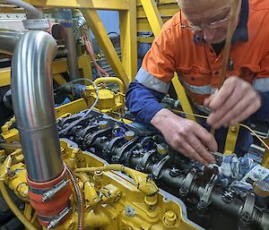 A man puts oil a large yellow machine