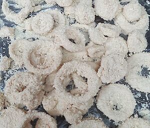 Tray filled with crumbed onion rings ready for frying