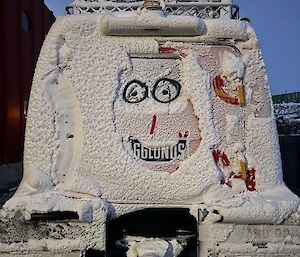 Snow covered hagglunds from rear, with smiling face drawn into snow on the back window