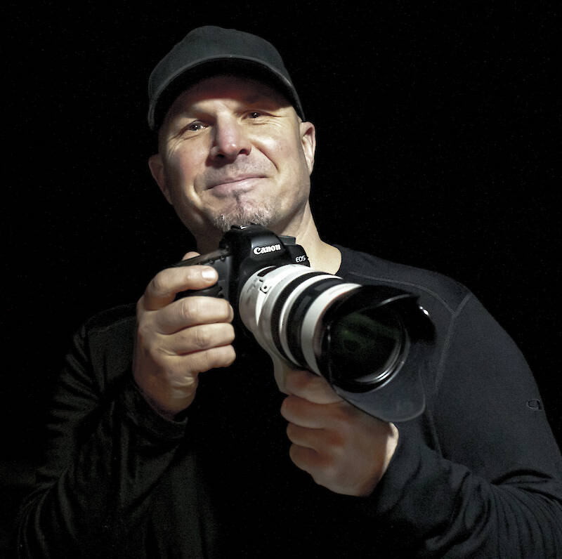Man dressed in black holding a long-lens camera