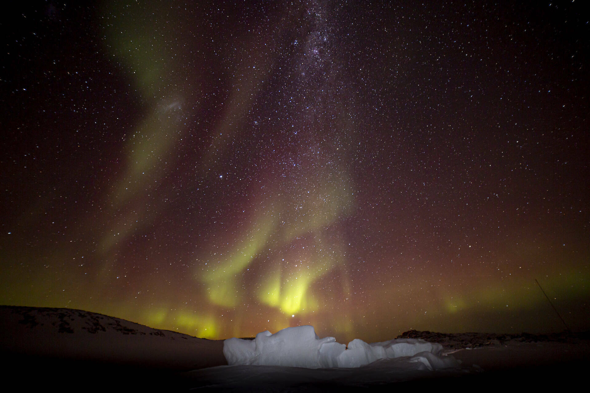 A green aurora over an iceberg