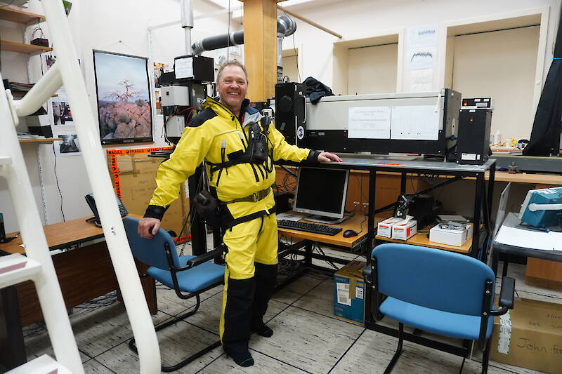 Scientist standing beside scientific equipment in an office.