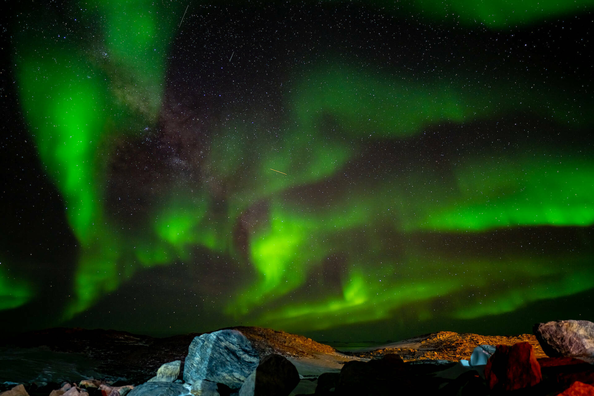 Green aurora at Casey with rocks in the foreground.