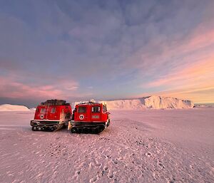 Red Hagglunds vehicle on sea ice with icebergs in the background