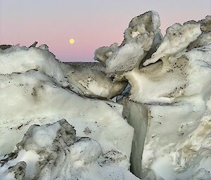 Ice mixed with dirt with the moon and a purple sky in the background