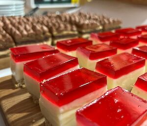 A close up photo of the strawberry jelly cheesecake slice with opera cake in background