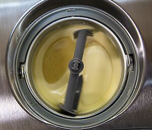 A top-down view of an ice cream maker churning a custard-like mixture