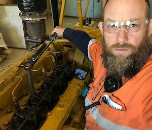 Man takes selfie of himself adjusting cylinder head of engine