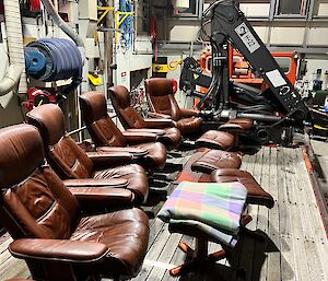 Leather arm chairs with matching poufs lined up and ready for a movie on the back trailer of a vehicle inside a workshop