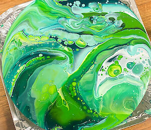 Photo of green paint poured onto canvas marbled
