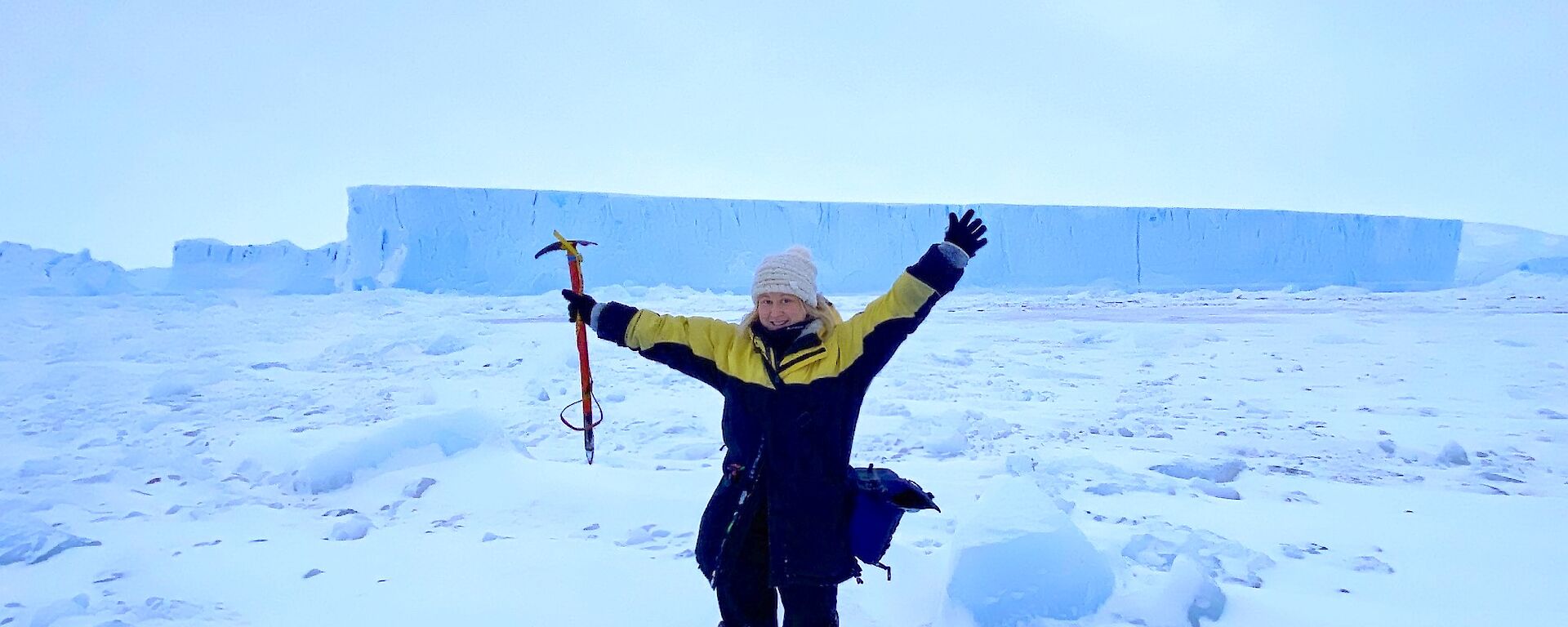 Alana standing in front of an iceberg with arms in the air
