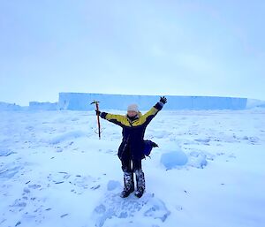 Alana standing in front of an iceberg with arms in the air