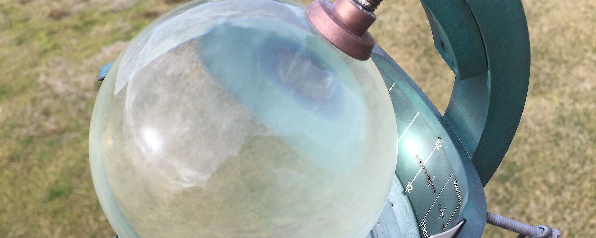 A glass globe sits in a frame and is used to measure hours of sunshine