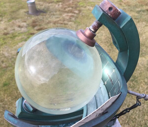 A glass globe sits in a frame and is used to measure hours of sunshine