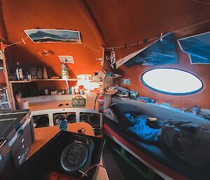 Internal picture of the googie hut, showing table in foreground, bed against the far wall with a round window above