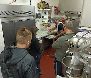 A group of people watching pasta being made in an industrial kitchen