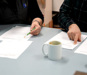 Close up of scripts on table with hands pointing to lines of text