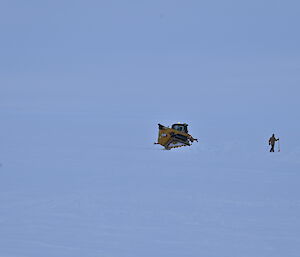 A bob cat and a person with a shovel surrounded by snow