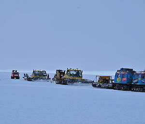 Blue Hägglunds followed by two groomers and a red Hägglunds