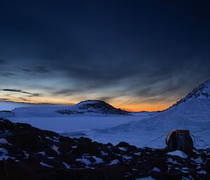 Rocky islands amongst the sea ice at sunset with small accommodation van in the right foreground