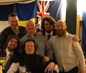 a group of men posing for a group photo in front of some flags