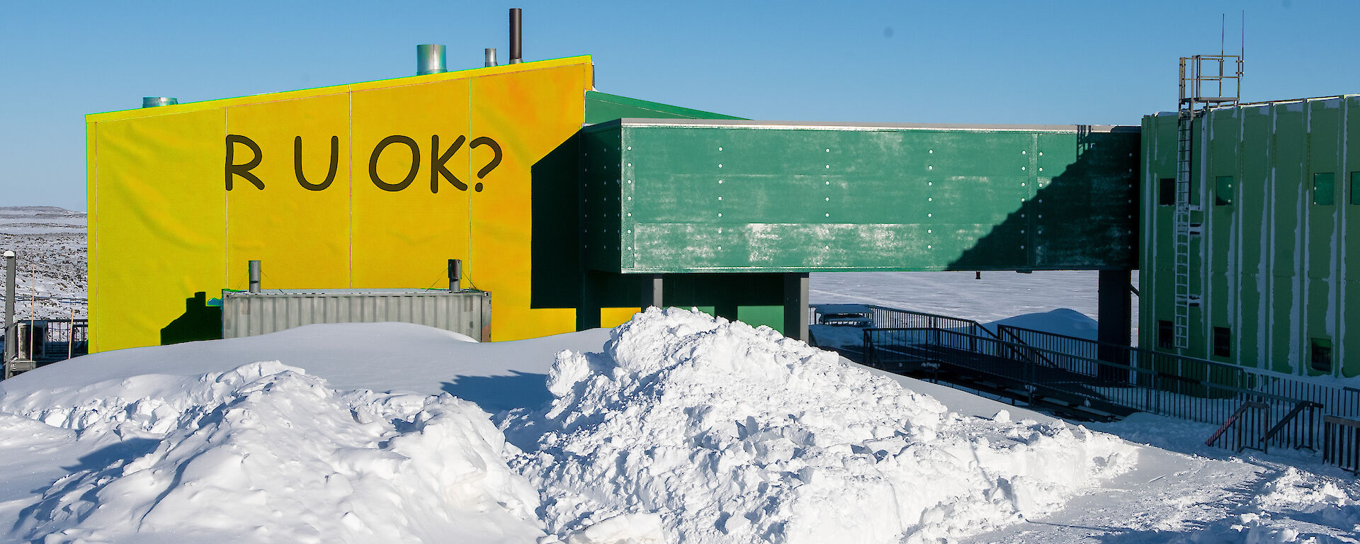 Yellow R U OK? sign covering part of a green building