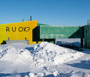 Yellow R U OK? sign covering part of a green building