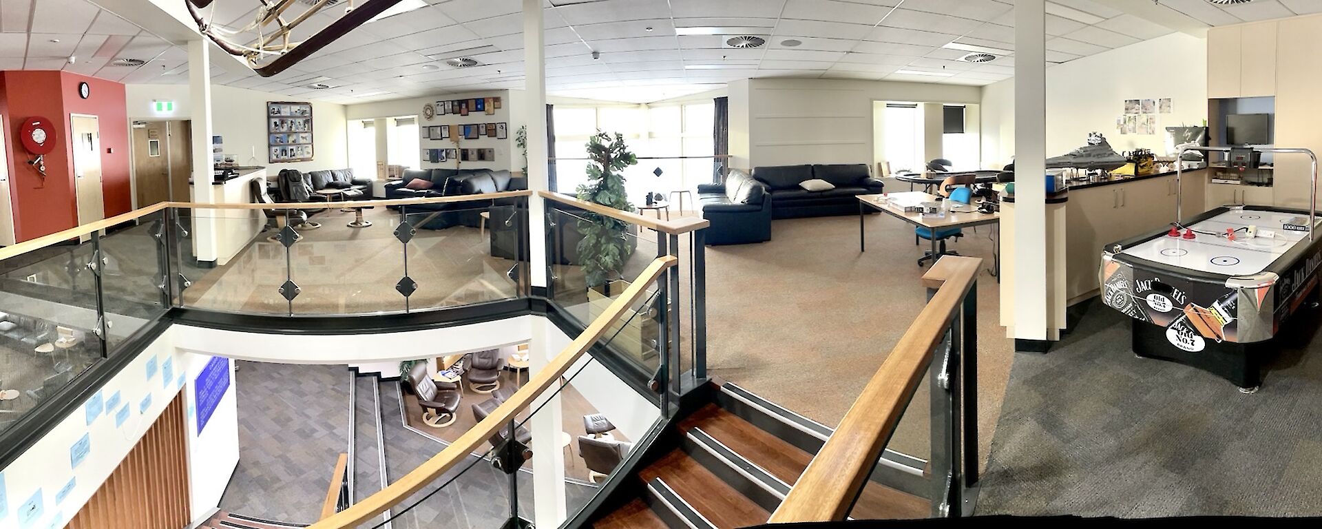 A panoramic photo of a living area, including sofas, photos and plaques hung on the wall, an air hockey table and some large, elaborate Lego constructions