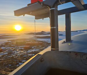 View from on top of wind turbine showing station from above and sunrise in distance