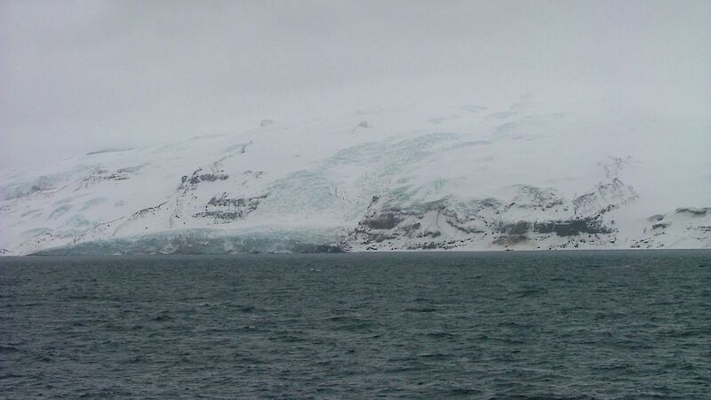 Glacier and ice covered island viewed from ship in over casted conditions