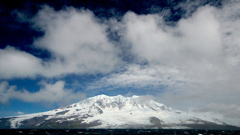 Ice covered slopes of Heard Island viewed from ship at sea.