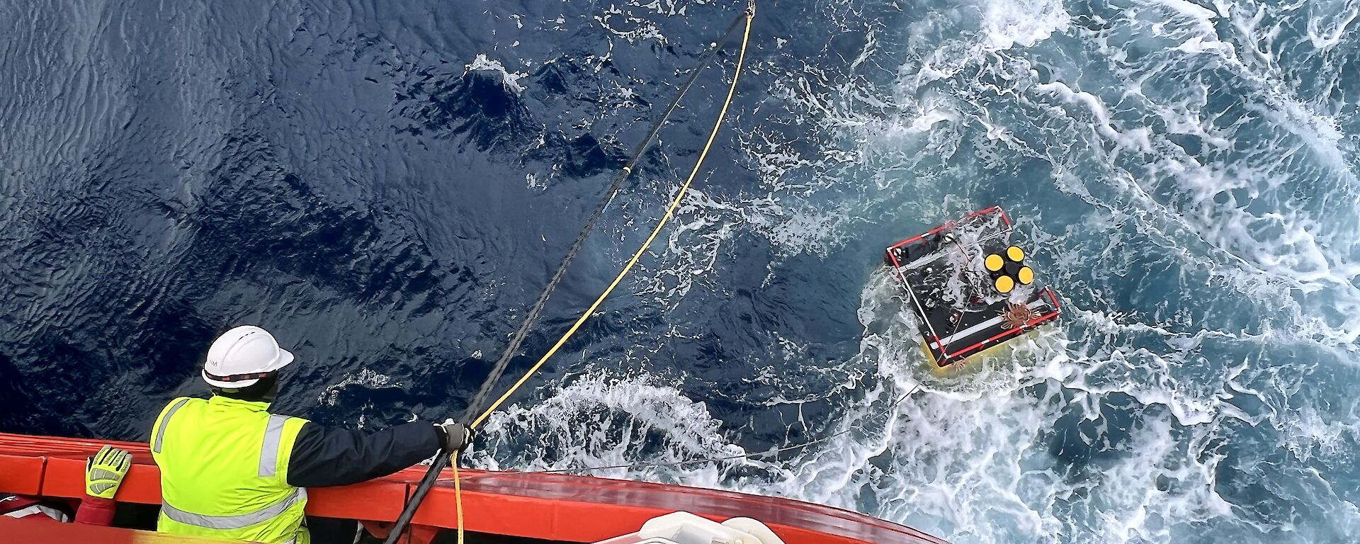 A krill monitoring device recovered from the Southern Ocean with a man leaning over a ship