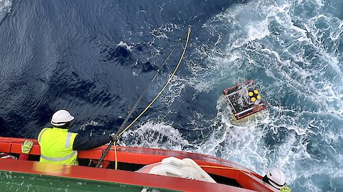 A krill monitoring device recovered from the Southern Ocean with a man leaning over a ship