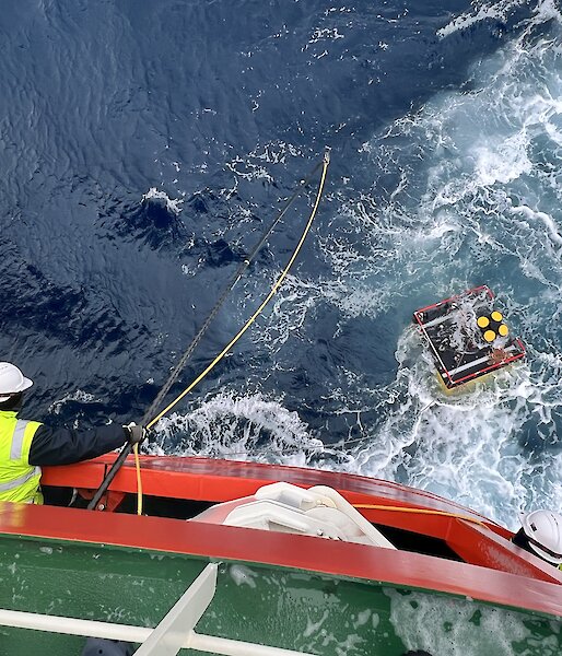A krill monitoring device recovered from the Southern Ocean with a man leaning over a ship