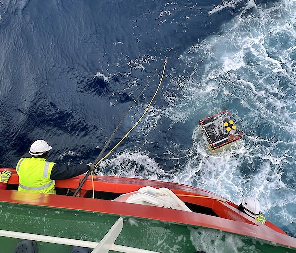 A krill monitoring device recovered from the Southern Ocean with a man leaning over a ship