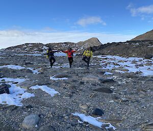 Three happy people standing in the snow and rocks