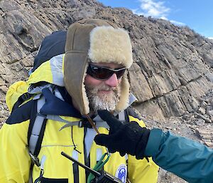 A person in a yellow jacket and lambswool hat with a frozen beard