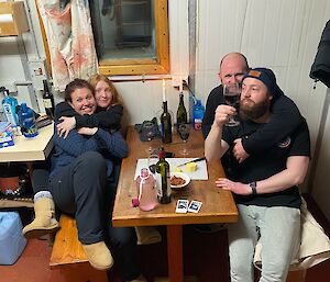 Four happy people sitting at a wooden table in a hut