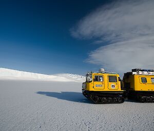 Foreground yellow Hägglunds on the sea-ice, in the distance ice cliffs