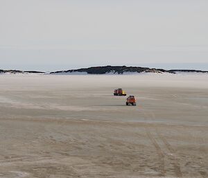 Two Hägglunds travel across the sea ice leaving station