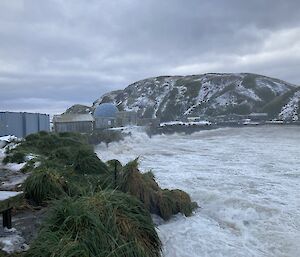 Waves wash shoreline near buildings on snowy island