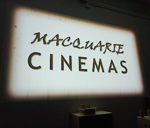 A large white cinema screen with showing a black and white sign saying "Macquarie cinemas"