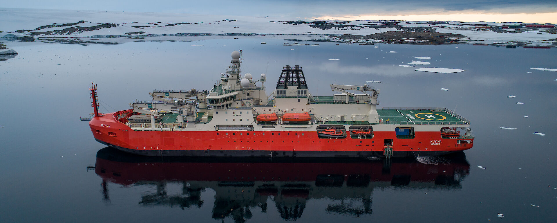 Antarctic icebreaker RSV Nuyina on a mirror-smooth bay in Antarctica.