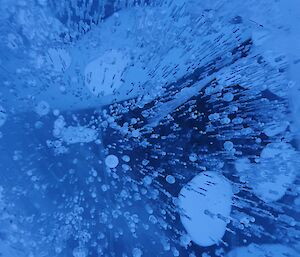 Close up of frozen blue water with bubbles captured