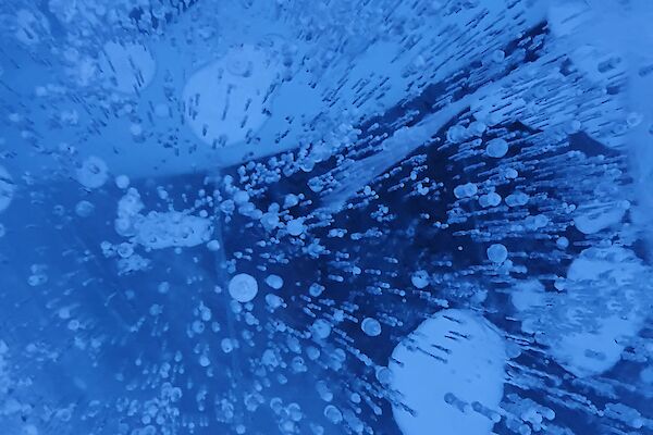 Close up of frozen blue water with bubbles captured