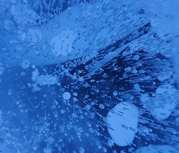 Close up of frozen blue water with bubbles captured