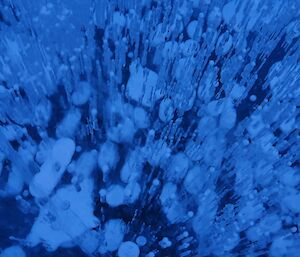 Close up of frozen blue water with bubbles captured