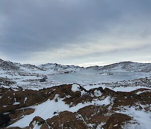 Brown hills, snow and ice under a grey sky