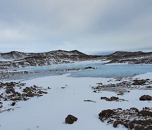 Brown hills, snow and ice under a cloudy sky